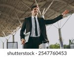 Bottom view happy young traveler businessman man wearing black dinner suit walk go outside at international airport terminal hold closed laptop pc computer catch taxi Air flight business trip concept