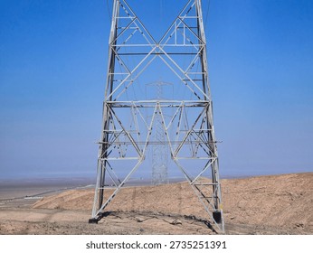 Bottom view of a high-voltage tower in alignment with other towers