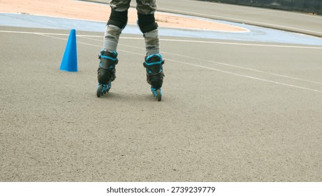 Bottom view a kid is playing roller skate or roller blade on concrete ground  Extreme sport and recreation activity photo. A kid practicing  In line skate with cones.