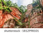 Bottom view of the Leshan Giant Buddha. Green trees and blue sky in background. The largest and tallest stone Buddha statue in the world carved out of a red cliff at the Mount Emei Scenic Area, China.