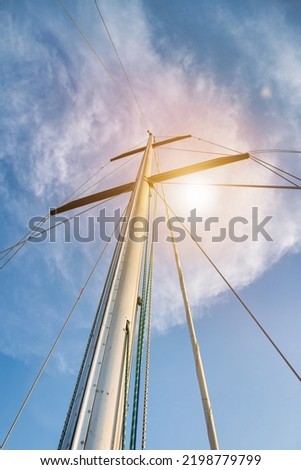 Bottom view mast boat against sky with cumulus clouds in sea. Mast of sailing yacht with ropes without sail at blue sky background. Transportation, cruise, sailing, yachting concept. Copy space