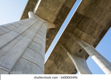 Bottom view of modern concrete highway bridge with massive pillars. Tall concrete pillars holding a road bridge. The converging lines show the perspective of space.