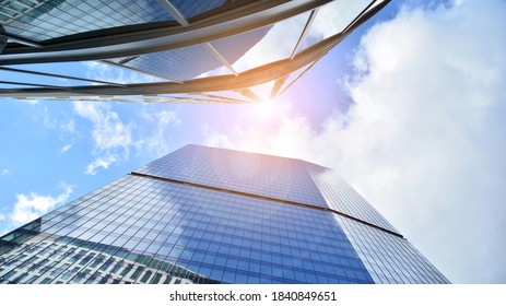 Bottom view of modern office buildings in the business district. Skyscraper glass facades on a bright sunny day with sunbeams in the blue sky. - Shutterstock ID 1840849651