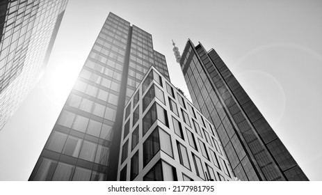 Bottom view of modern skyscraper in business district against blue sky. Looking up at business buildings in downtown. Rising sun on the horizon. Black and white. - Shutterstock ID 2177981795