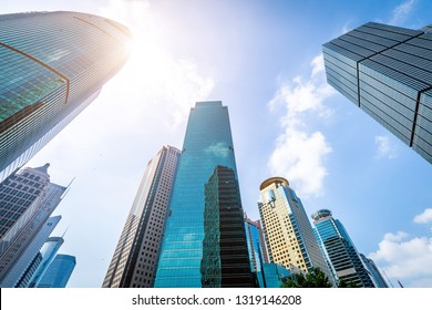 Bottom view of modern skyscrapers in business district against blue sky