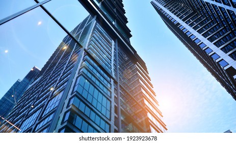 Bottom view of modern skyscrapers in business district against blue sky. Looking up at business buildings in downtown. Rising sun on the horizon. - Shutterstock ID 1923923678