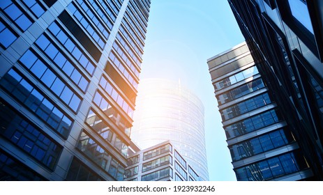 Unten Blick auf moderne Wolkenkratzer im Geschäftsviertel gegen blauen Himmel. Schauen Sie auf Geschäftsgebäude in der Innenstadt. Steigende Sonne am Horizont.