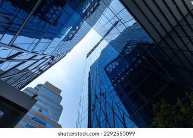 Bottom view of modern skyscrapers in business district against blue sky. Worm's-eye view architecture and blue background