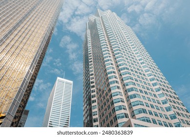 Bottom view of modern skyscrapers offices in a financial district against a suggestive blue sky and soft clouds. - Powered by Shutterstock