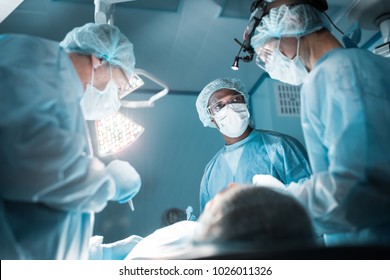 bottom view of multicultural surgeons operating patient in operating room