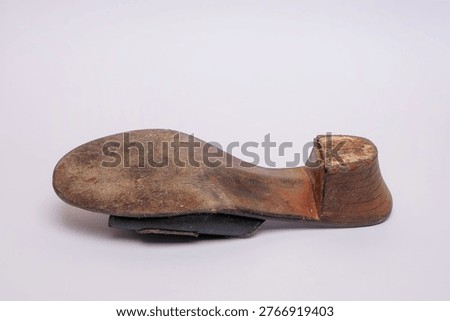 Bottom view of an old worn leather sandal with a damaged wooden heel isolated on white. This image highlights concepts of poverty, hardship, and the need for repair or replacement