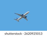 Bottom view of passenger plane taking off in blue sky
