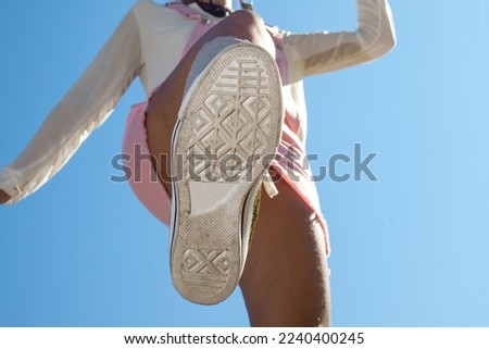 Bottom view of shoe sole, Bottom view boot sole of woman jumping with a blue sky background. Bottom view of woman jumping over the camera and close-up of the sole of the boot