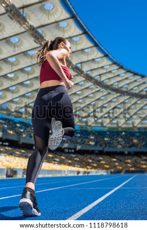 bottom view of sportive young woman running on track at sports stadium