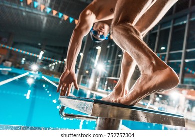 bottom view of swimmer jumping into competition swimming pool 
