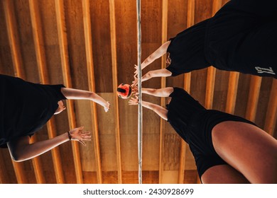 Bottom view of teenage volleyball players blocking the ball on their training. Low angle view of female volleyball team practicing volleyball moves and blocking the ball over net during the training. - Powered by Shutterstock