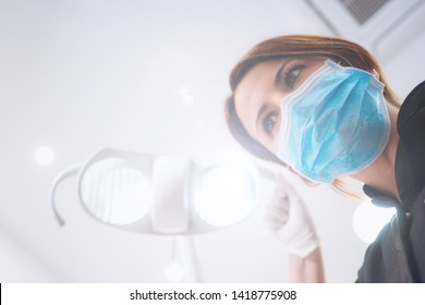 Bottom View Of Two Women Dentists In Surgical Mask Holding Tools And Looking At Camera. Patient Point Of View To Dentist.