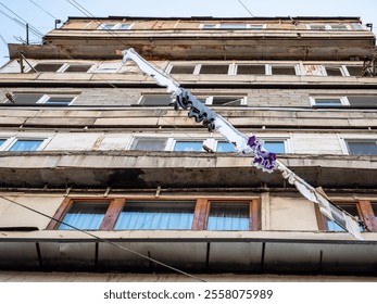 bottom view of washed clothes drying on clothesline and facade of multi-story residential building in Yerevan on autumn evening - Powered by Shutterstock