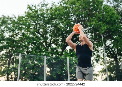 Bottom View Young Sporty Muscular Strong Caucasian Sportsman Man 20s Wear Sportswear Training Shooting Free Throw Play With Ball At Basketball Game Playground Court Outdoor Courtyard Sports Concept.