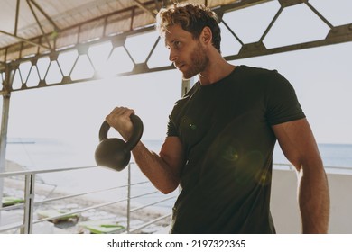 Bottom view young strong sporty athletic toned fit sportsman man wearing sports clothes warm up training work out lifts weight kettlebell at outdoor gym sea beach outdoor seaside in summer day morning - Powered by Shutterstock