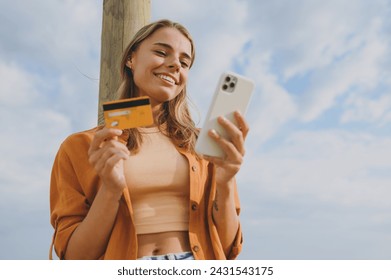 Bottom view young woman wears orange shirt casual clothes using mobile cell phone credit bank card shopping online walk on sea ocean sand shore beach outdoor seaside in summer day. Lifestyle concept - Powered by Shutterstock