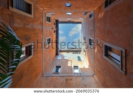 Bottom wide angle view of historic inner courtyard with beautiful facade building complex with blue sky and clouds in Rome, Italy. Geometric shape