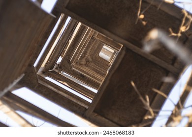 Bottom-up perspective of the rusty metal lattice structure that forms part of the tower. The structure forms an intricate pattern of squares and rectangles that extend into the blue sky - Powered by Shutterstock