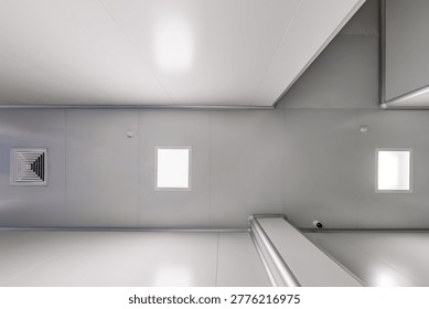 bottom-up view of the ceiling with industrial lighting and ventilation