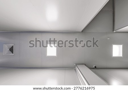 bottom-up view of the ceiling with industrial lighting and ventilation