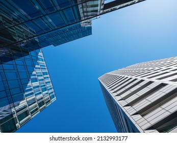 Bottom-up view of modern skyscrapers over blue sky background