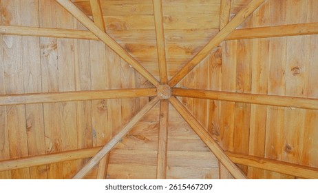 Bottom-up view of a wooden ceiling with symmetrical patterns. Traditional craftsmanship and geometric design create a warm, rustic architectural charm.

