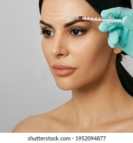 Botulinum toxin injections in a woman's forehead for blocking mimic wrinkles. Beautiful face with arrows, wrinkles removal concept - Shutterstock ID 1952094877