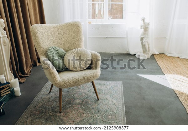 boucle\
chair with cushions in the middle of the room. room interior with\
vintage armchair, white walls and antique sculpture of a woman\
without arms. cozy room filled with natural\
light