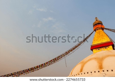Boudhanath Stupa (also known as Bouddha Stupa or Khasti Chaitya) at sunset in Kathmandu city, Nepal. Prayer flags sways on the wind. No people. Copy space for your text. Religious architecture theme.