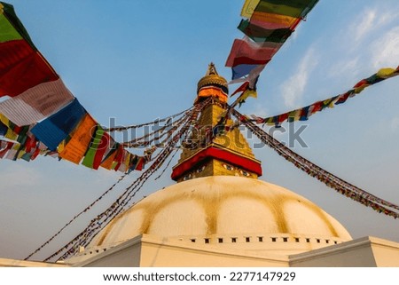 Boudhanath Stupa (also known as Bouddha Stupa or Khasti Chaitya) at sunset in Kathmandu city, Nepal. Prayer flags sways on the wind. No people. Religious architecture theme.