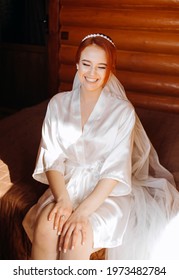 Boudoir Bride's Morning. Cute Red-haired Girl In Her Wedding Day.  Luxurious Bride In A Beautiful Satin Robe