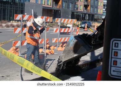 Boulder, CO USA - April 8, 2022: Construction Worker Crew Pour Black Asphalt To Fill A Hole In The Road. Road Maintenance. Heavy Machinery.