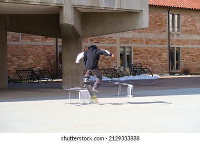 Boulder, CO USA - February 15, 2022: A Young Man Skateboards Across Outdoor Furniture On A Sunny Winter Day