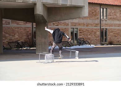 Boulder, CO USA - February 15, 2022: A Young Man Skateboards Across Outdoor Furniture On A Sunny Winter Day