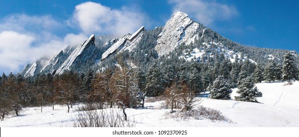Boulder Colorado Flatirons frosted with blowing snow against a clear blue sky.