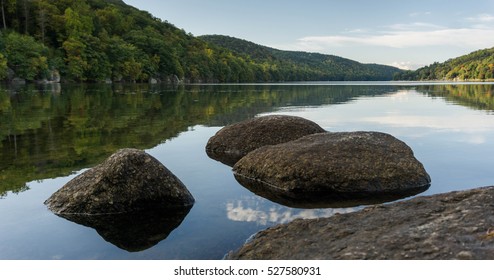 boulders in a lake with reflection and background in New England
