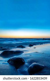 Boulders Stones On The Beach Of The Baltic Sea, The Eastern Coast Of The Baltic. Sunset And Long Exposure, Beautiful Blue Sunset, Phone Orientation On The Wallpaper.