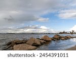 Boulders in the water of the Wolderwijd with the monument to Allied airmen near Harderwijk, Netherlands in the background