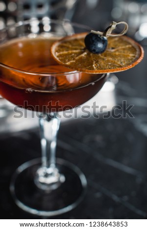 The Boulevardier Cocktail with orange chips on top. On a bar desk