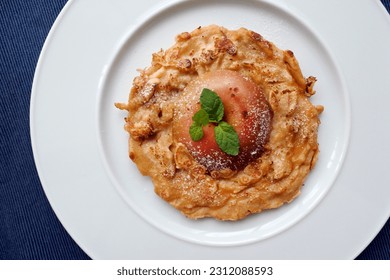 Bouligou du Limousin or crêpe aux pommes, is French apple pancake traditional dessert in Limousin area. Whate plate. Blue background.