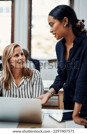 Bouncing ideas off of one another. an attractive businesswoman helping a female colleague in the office.