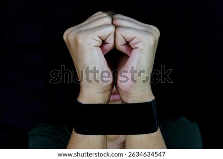Bound hands with dark background symbolizing restriction, anxiety, and and emotional pain.