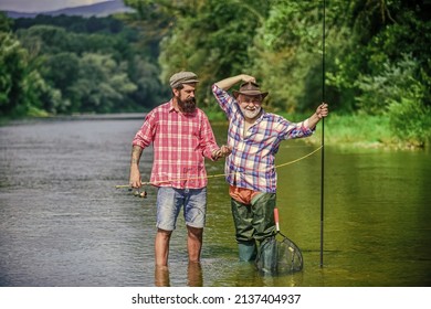 Bound Together In Love. two happy fisherman with fishing rods. summer weekend. mature men fisher. father and son fishing. hobby and sport activity. Trout bait. male friendship. family bonding