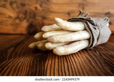 Bound white asparagus on rustic wood. Seasonal vegetable for healthy nutrion. Background with short depth of field and space for text.