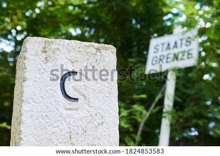 Boundary stone between Czech republic and Germany. Sign in background: Staats Grenze (Translation: State Border) in Sumava National Park (Bohemian Forest), Czech Republic and Germany borders